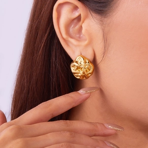 Detail of a model wearing a gold geometric earring with irregular crumpled metal texture
