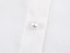 Macro detail of elegant pearl button and fine woven fabric on a white lace shirt