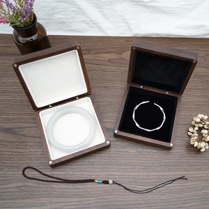 Detailed top view of a white jade bangle and silver bracelet in dark wood jewelry boxes