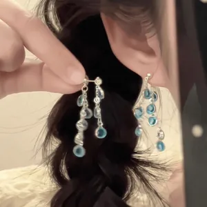 Gros plan de boucles d'oreilles à pampilles argentées avec gemmes bleues
