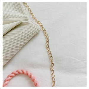 Detail of off-white corduroy bag with gold metal chain and pink resin handle