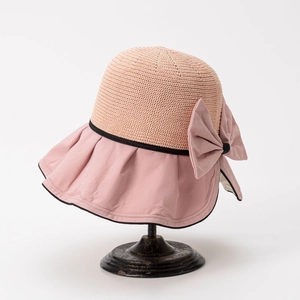 Detail of sun hat with beige woven crown, pink brim and elegant black trim bow