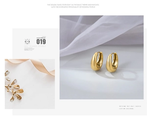 Detailed view of chunky golden oval hoop earrings resting on elegant white satin silk