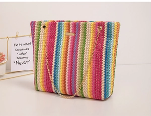 Macro detail of multi-colored woven straw bag featuring gold chain strap and metal nameplate
