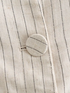 Detail of pinstriped vest showing woven linen texture and fabric covered button