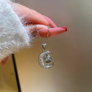 Detail of moon pendant with micro-pave zircons and projection stone held in hand