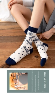 Detail of white and navy mid-calf socks with polka dots and peach text embroidery