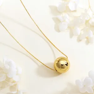 Detailed view of mirror-polished gold sphere pendant on a delicate box chain necklace
