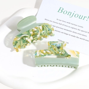 Detail of green and yellow marble pattern acrylic hair clips on a white tray