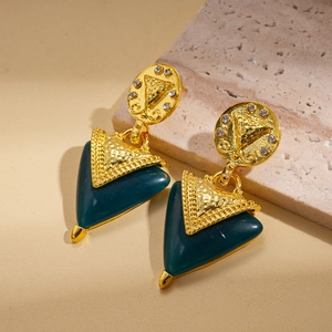 Détail de boucles d'oreilles triangulaires en résine vintage avec cristaux et fini doré martelé