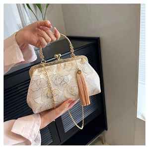 Close-up of beige vintage shell bag with floral embroidery, gold chain, and tassel detail