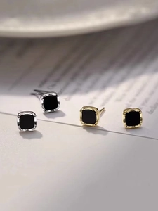 Makroaufnahme von minimalistischen gold-silbernen quadratischen Ohrringen mit Schwarz