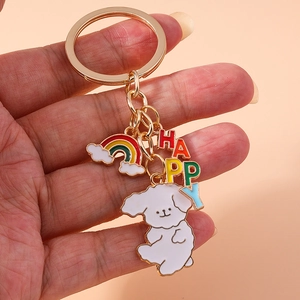 Detail of a gold-tone keychain with a white dog charm, rainbow cloud, and HAPPY letters