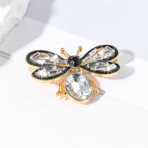 Macro shot of bee brooch detailing golden wings with crystals and large faceted gemstone