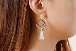 Detail view of stylish geometric mixed-metal drop earrings worn by a model
