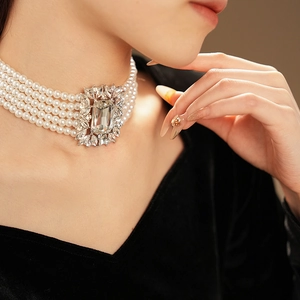 Detail of layered pearl choker featuring a square crystal pendant with zircon accents