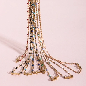 Detail of colorful beads and gold Ankh cross pendant on a stainless steel necklace