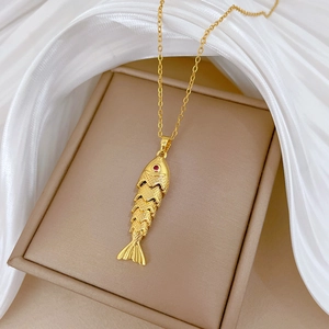 Détail d'un pendentif carpe koi articulé doré avec yeux en gemme rouge sur soie blanche