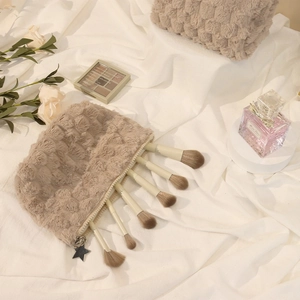 Beige plush checkered makeup bag with star pendant, featuring five brushes on white fabric