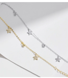 Dettaglio di bracciali in argento S925 oro e argento con pendenti a stella e piccoli diamanti