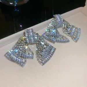 Macro detail of silver bow tassel earrings with sparkling crystals on display tray