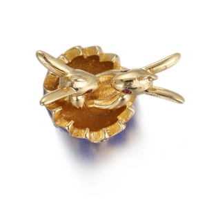 Macro shot of golden rabbit charm ring with red gemstone eyes on a white background