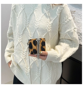Detailed macro of a mini leopard print crossbody bag with metallic chain on white knit