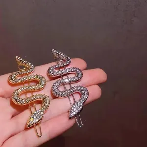 Macro detail of snake-shaped hair clips in gold and silver finish with sparkling crystals