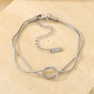 Detailed macro view of silver stainless steel double-layered knot chain bracelet on stone