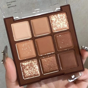 Nine-color chocolate brown eyeshadow palette with matte and shimmer textures in hand