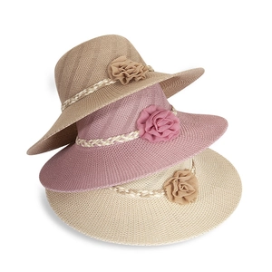 Three colors of straw sun hats with fabric flower decorations in a stacked arrangement