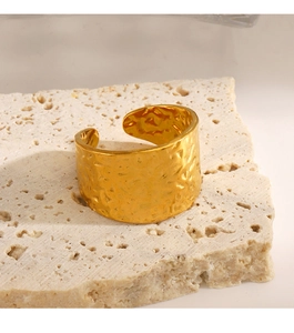 Detailed view of wide gold-toned stainless steel ring with hammered texture on stone base
