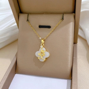 Detailed macro view of gold rose and clover pendant necklace with white stone inlay