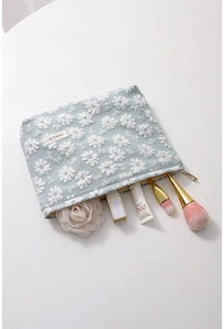 Gros plan sur la trousse de maquillage en toile bleue avec broderie marguerite et fermeture