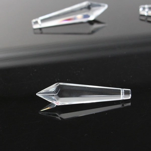 Macro view of faceted clear crystal prism pendants on a reflective black surface