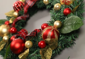 Close-up of Christmas wreath with red plaid bow, gold baubles, and green pine needles