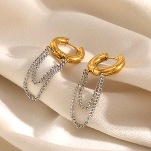 Detail of 18K gold chain tassel earrings on soft beige fabric for an elegant look