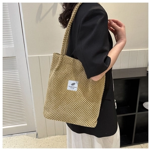 Detail view of khaki corduroy tote bag with white woven label showing texture and strap