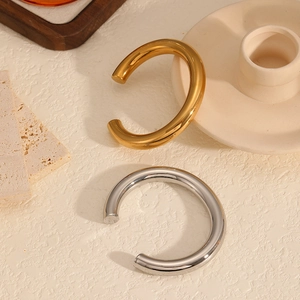 Detailed view of polished C-shaped hollow bangles in gold and silver stainless steel
