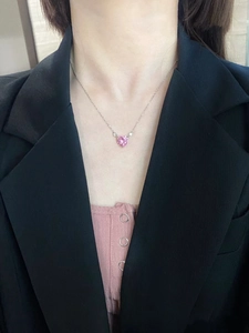 Detailed view of pink heart pendant necklace worn on neck with minimalist silver chain
