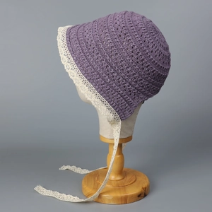 Detailed side view of purple knitted sun hat with intricate lace trim and ribbon ties.