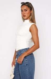 Close-up of ruched side texture on a slim fit white mock neck sleeveless top