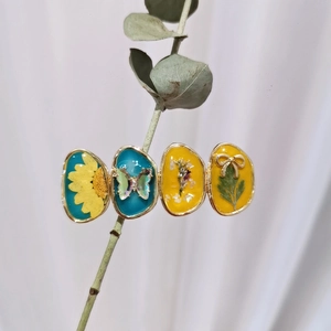 Detail view of handmade gold hair clip with butterfly and dried flower resin charms