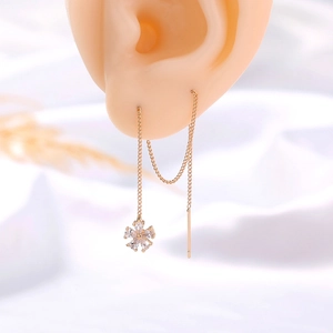 Macro view of long gold tassel earring with sparkling zircon flower pendant on ear model