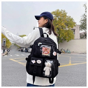 Outdoor shot of a black canvas backpack featuring cute cartoon patches and a plush bear