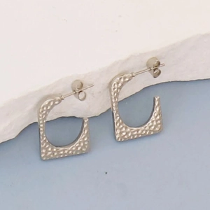Detailed close-up of silver irregular square earrings with hammered texture and butterfly back