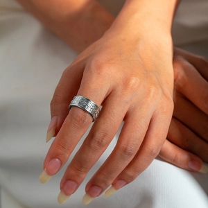 Detailed close-up of a silver titanium steel open ring with engraved eye and dot patterns