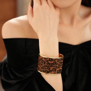 Close-up of wide gold-plated leopard print cuff bracelet worn on female wrist