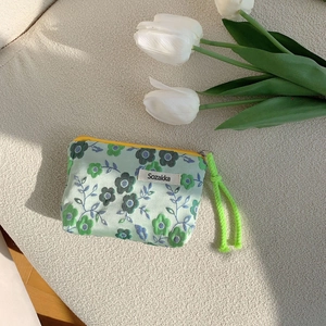 Detailed macro view of floral canvas makeup bag with green strap and yellow zipper