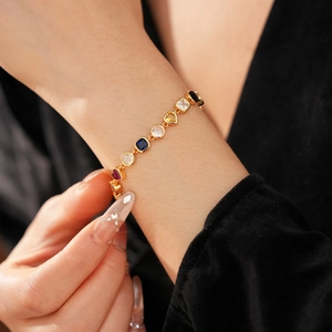 Gros plan d'un bracelet vintage doré orné de zircons colorés en forme de cœur et ronds